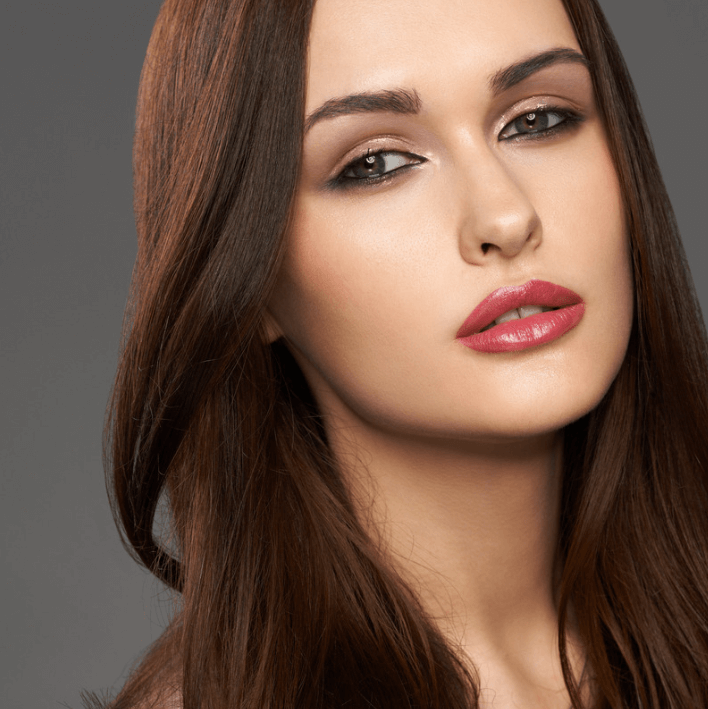Close-up of a model with smooth skin and long brown hair showcasing a natural makeup look.