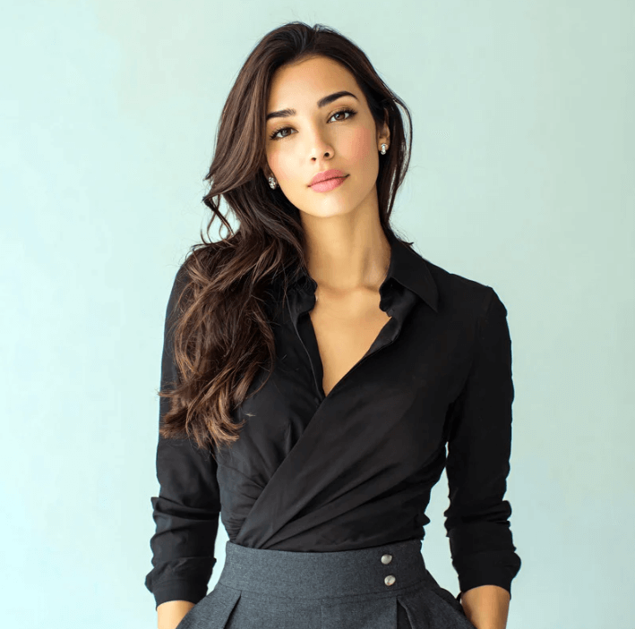 Portrait of a woman in a black blouse with long, wavy hair against a light background.