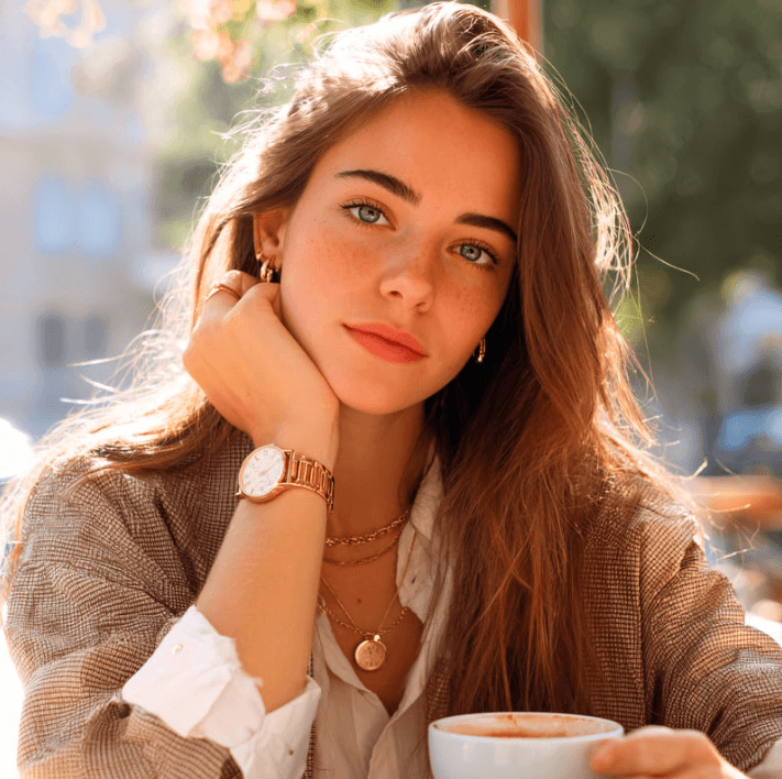 A woman enjoying coffee, showcasing natural beauty with radiant skin and soft makeup.